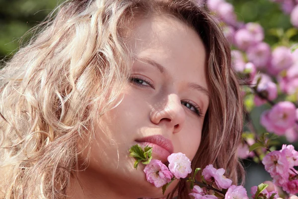 Mulher loira bonita entre flores rosa — Fotografia de Stock