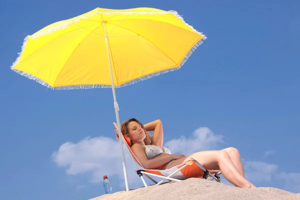 日光浴 下一把伞在海滩上的比基尼的金发女人 — 图库照片