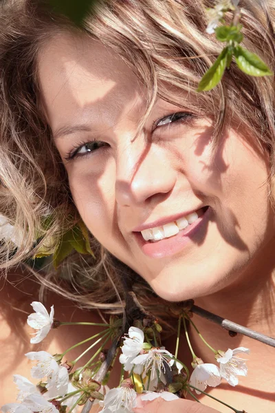 Schöne blonde Frau zwischen Baum mit weißen Blumen — Stockfoto