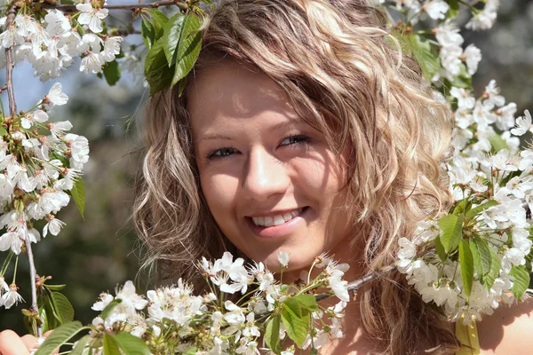 Hermosa mujer rubia entre el árbol con flores blancas — Foto de Stock