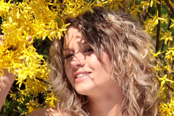 Mujer joven rubia en flores de forsythia amarillas —  Fotos de Stock