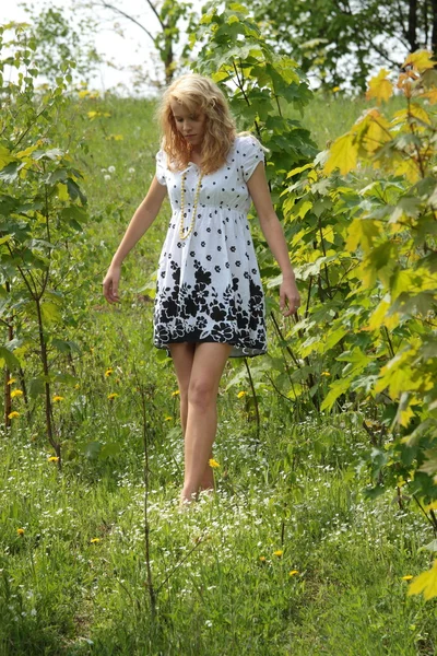 太陽を楽しんでいる黒と白のドレスを着ている美しい若いブロンドの女性 — ストック写真