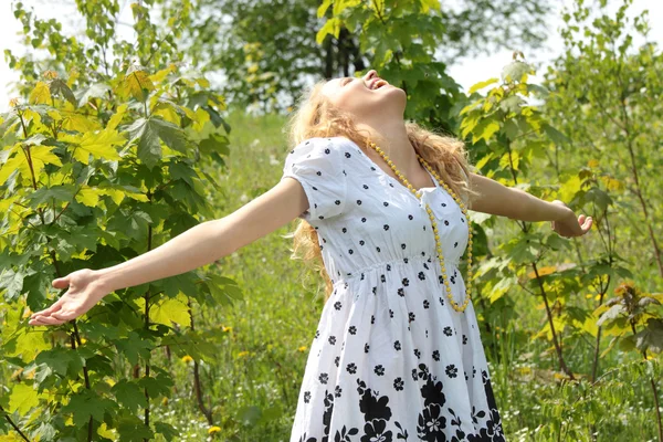 太陽を楽しんでいる黒と白のドレスを着ている美しい若いブロンドの女性 — ストック写真