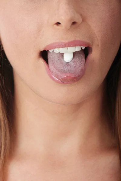 Jovem mulher tomando um comprimido . — Fotografia de Stock