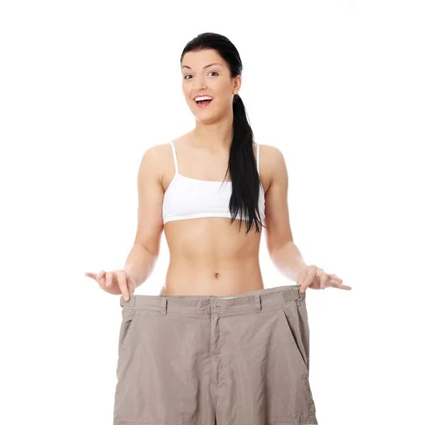 Молодая счастливая женщина показывает, как сильно она похудела — стоковое фото