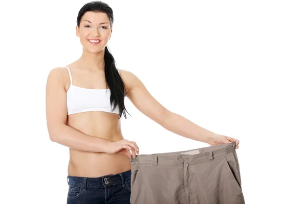 Молодая счастливая женщина показывает, как сильно она похудела — стоковое фото
