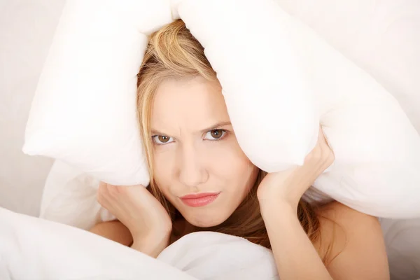 彼女の頭の上の枕とベッドの上の若い白人女性 不眠症の概念 — ストック写真