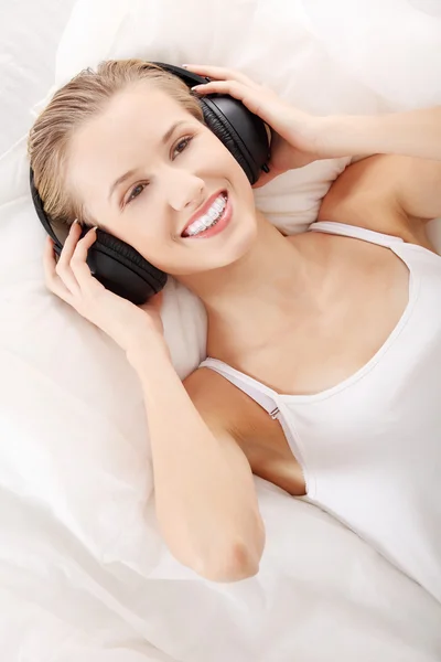 美しい女性は 自宅のベッドに横たわっている音楽を聴く — ストック写真