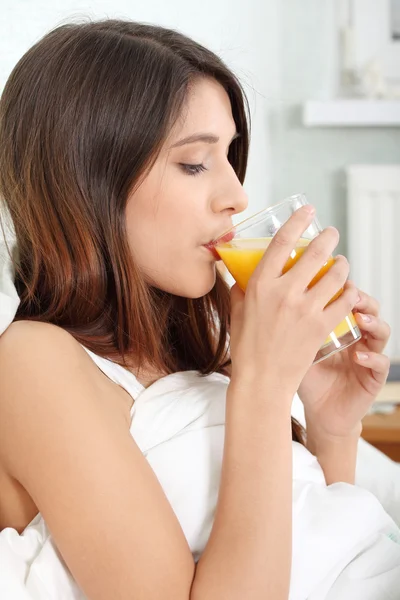 オレンジ ジュースを飲んでベッドに女性 — ストック写真