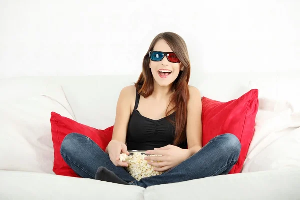 Beautiful young woman watching TV in 3d glasses — Stock Photo, Image