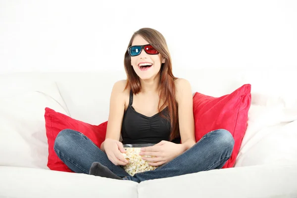 美しい若い女性の メガネでテレビを見てとポップコーンを食べて — ストック写真