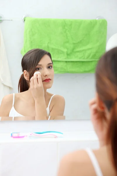 年轻美丽的白种女人清洗她的脸用棉垫在浴室 — 图库照片