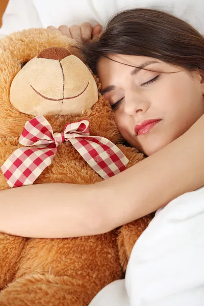 迷人的黑发姑娘和她的泰迪熊躺在床上 — 图库照片