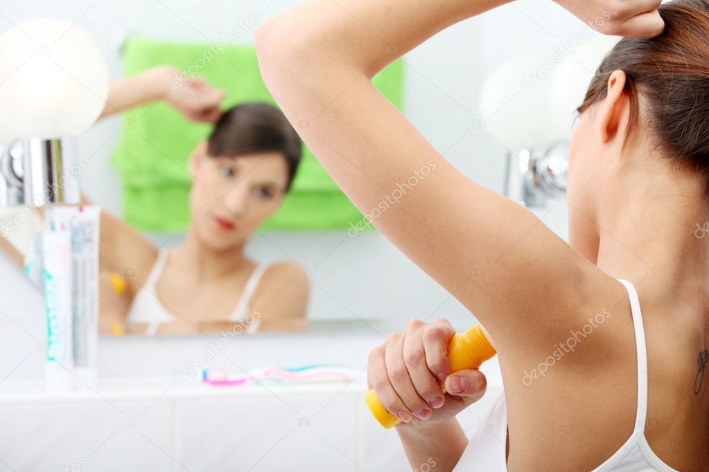 Young beautiful caucasian woman using deodorant at her bathroom