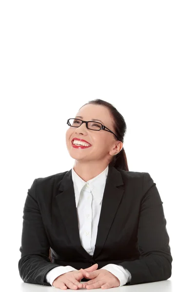 Zufriedene Geschäftsfrau hinter dem Schreibtisch, aufblickend — Stockfoto