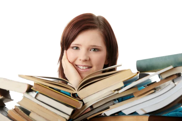 Ung kvinna sitter bakom böcker — Stockfoto