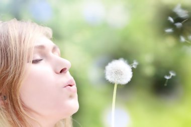 The blonde in park with a dandelion in hands clipart