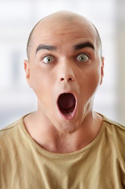 Closeup portrait of a shocked young man looking straight clipart