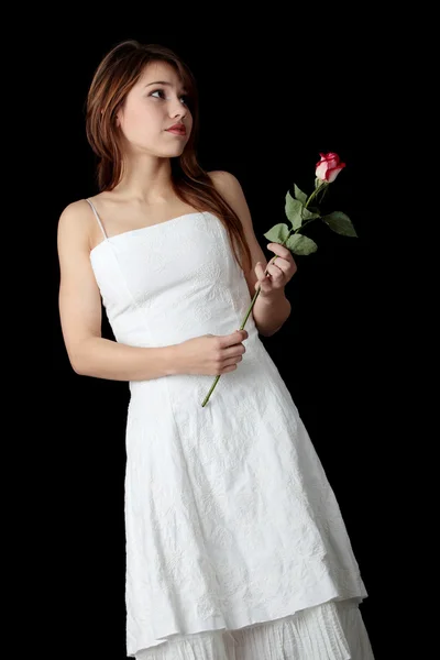 Mooie jonge vrouw in witte jurk met roos — Stockfoto