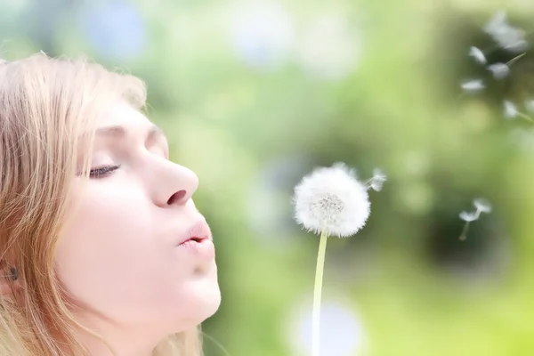 The blonde in park with a dandelion in hands — Stock Photo, Image