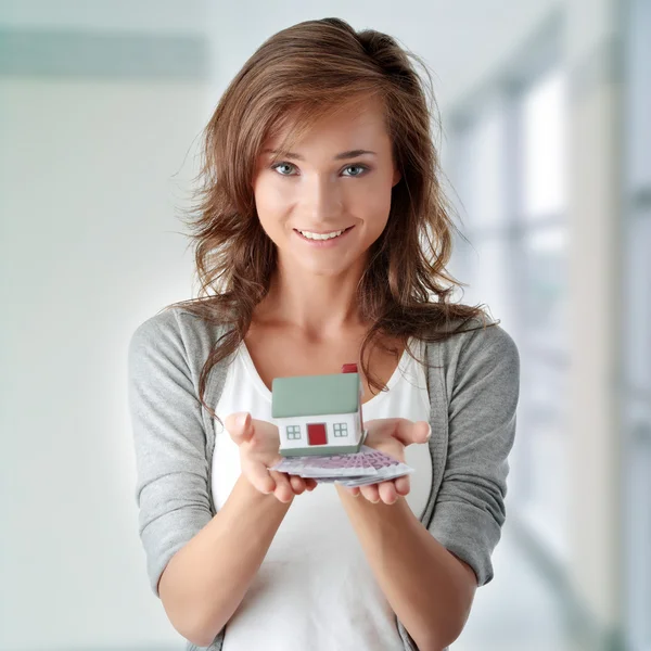 Mulher segurando notas de euros e modelo de casa — Fotografia de Stock
