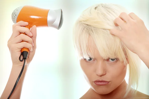 Sarışın kadın saç kurutma makinesi kullanma — Stok fotoğraf