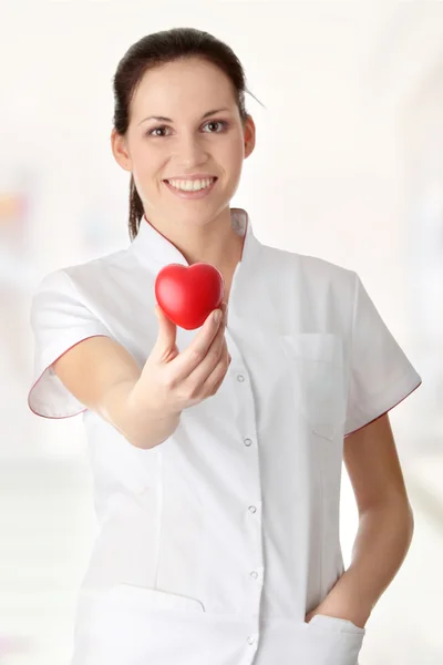 Ung sjuksköterska med hjärtat i handen — Stockfoto