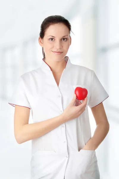 Jonge verpleegster met hart in haar hand — Stockfoto