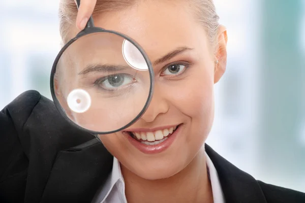 Business woman looking into a magnifying glass — Stock Photo, Image