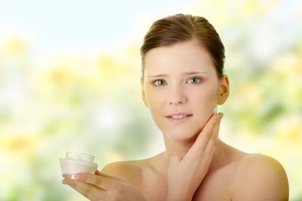 Frau cremt Gesicht mit Feuchtigkeitscreme ein — Stockfoto