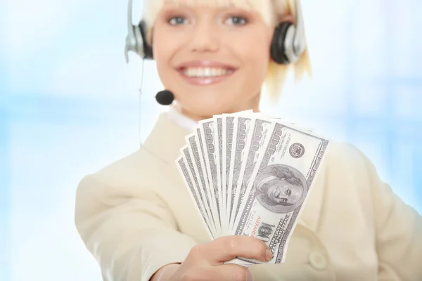 Γυναίκα των επιχειρήσεων με ακουστικό κρατώντας δολάρια — Φωτογραφία Αρχείου