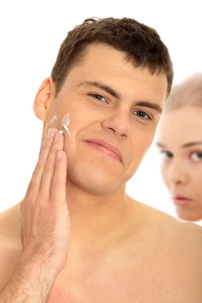 Szczęśliwy mężczyzna po goleniu nakłada krem nawilżający na twarz — Zdjęcie stockowe