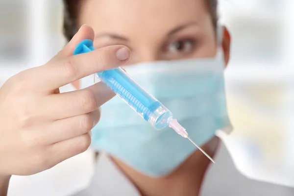 Mladá zdravotní sestra v masce s injekční stříkačkou — Stock fotografie