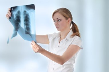 Female doctor examining a chest x-ray photo sca clipart
