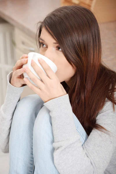 Mutfakta kahve veya çay sahip genç bir kadın — Stok fotoğraf