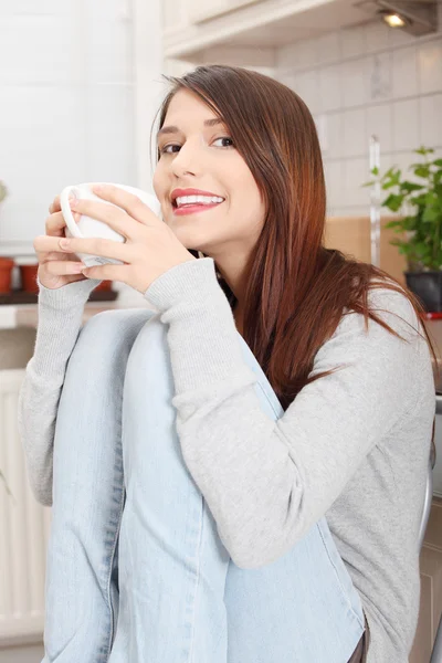 Mujer joven tomando café o té en la cocina — Foto de Stock
