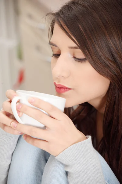 台所でコーヒーまたは紅茶を持つ若い女性 — ストック写真