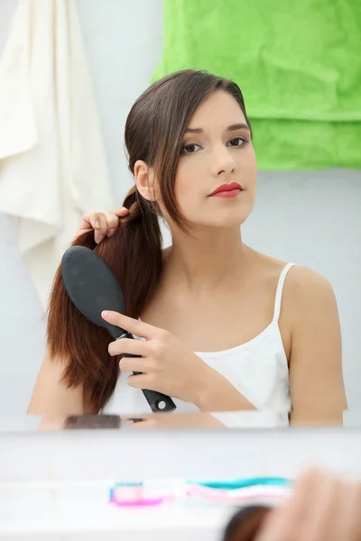 Bella giovane donna spazzolando i capelli — Foto Stock