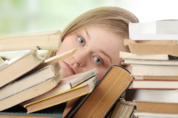 Giovane donna seduta dietro i libri — Foto Stock