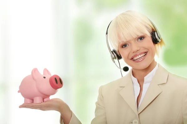 Mulher com fone de ouvido segurando porquinho banco — Fotografia de Stock
