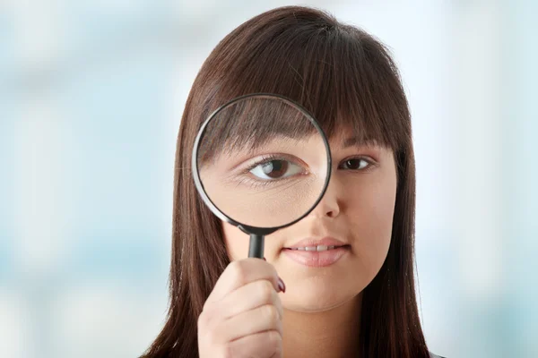 Businesswoman looking into a magniying glass — Stock Photo, Image