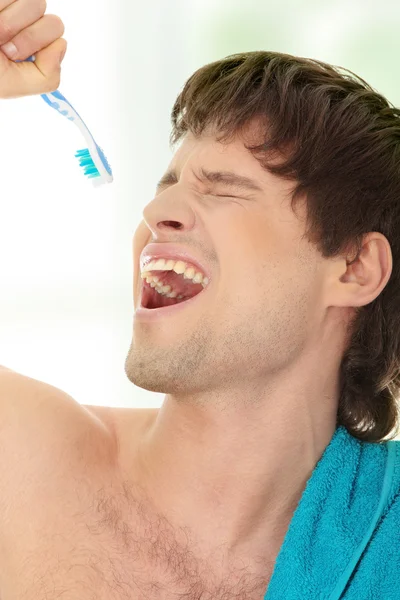 Молодой счастливый красивый мужчина поет зубной щетке — стоковое фото