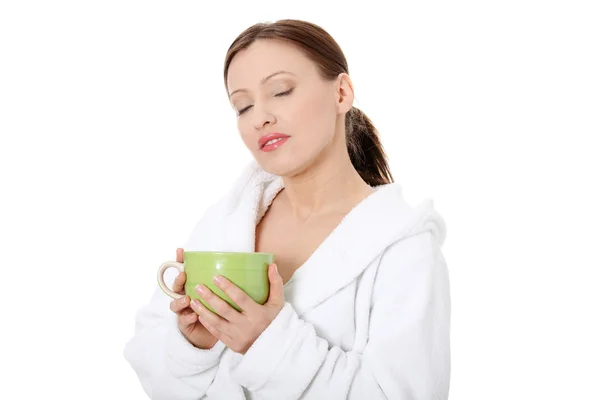 Mature lady in bathrobe drinking from mug — Stock Photo, Image