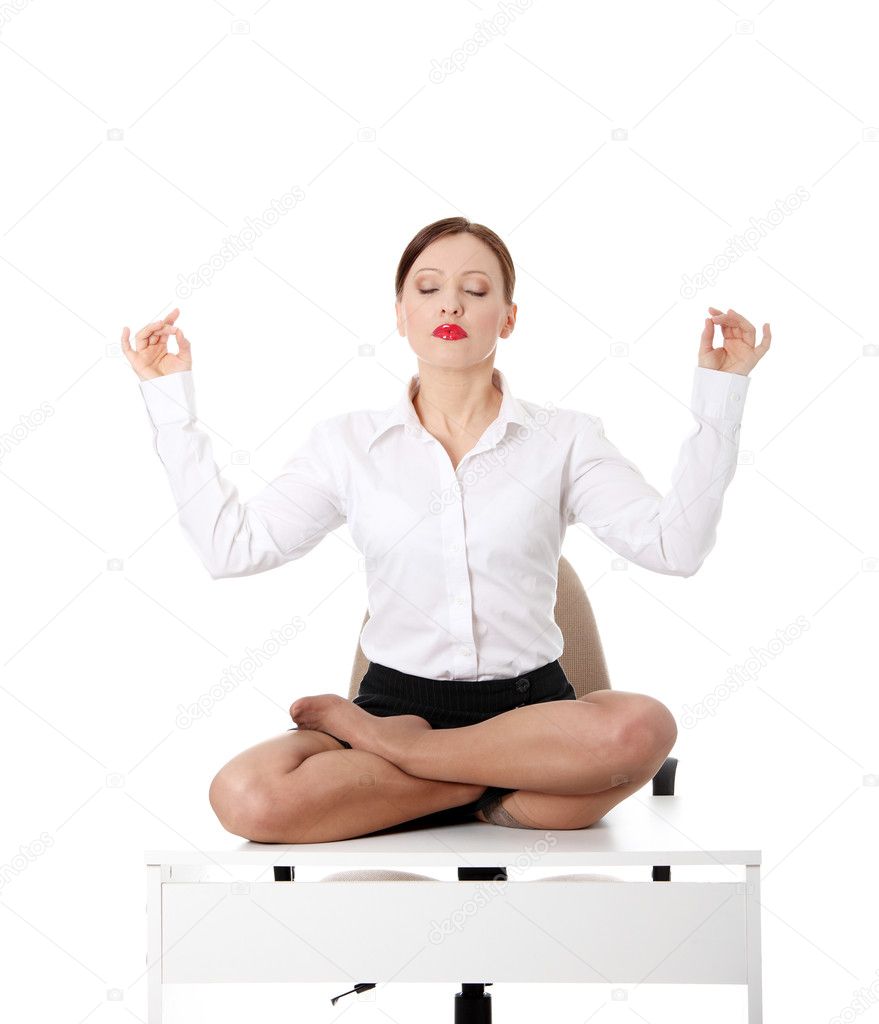Businesswoman sitting on white desk in lotus flower position