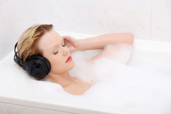 Mulher bonita com fones de ouvido no banho . — Fotografia de Stock