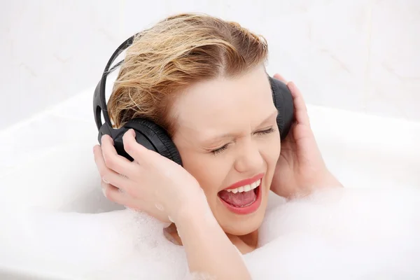 Hermosa mujer con auriculares en el baño . — Foto de Stock