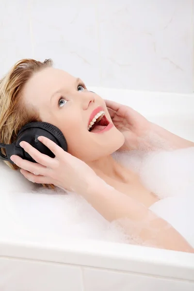 Vacker kvinna med hörlurar i badet. — Stockfoto