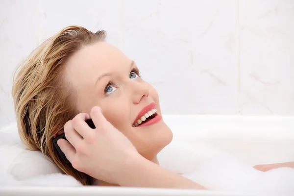 Hermosa mujer joven hablando por teléfono móvil mientras toma un baño . — Foto de Stock