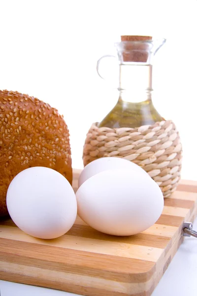 Świeże pieczywo, jajka i olej na pokładzie drewna — Zdjęcie stockowe