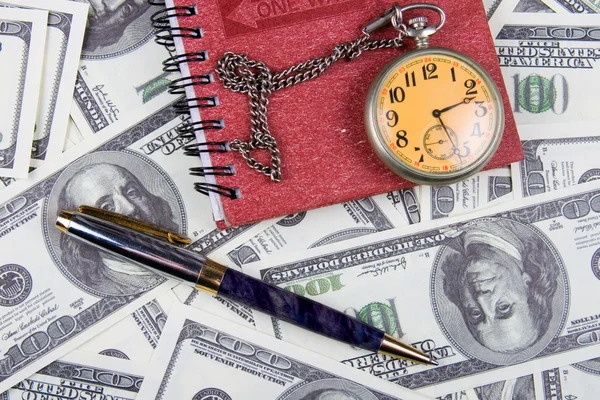 Taschenuhr, Notizbuch und Stift auf einem Stapel Dollars, die Zeit und Zeit reflektieren. — Stockfoto
